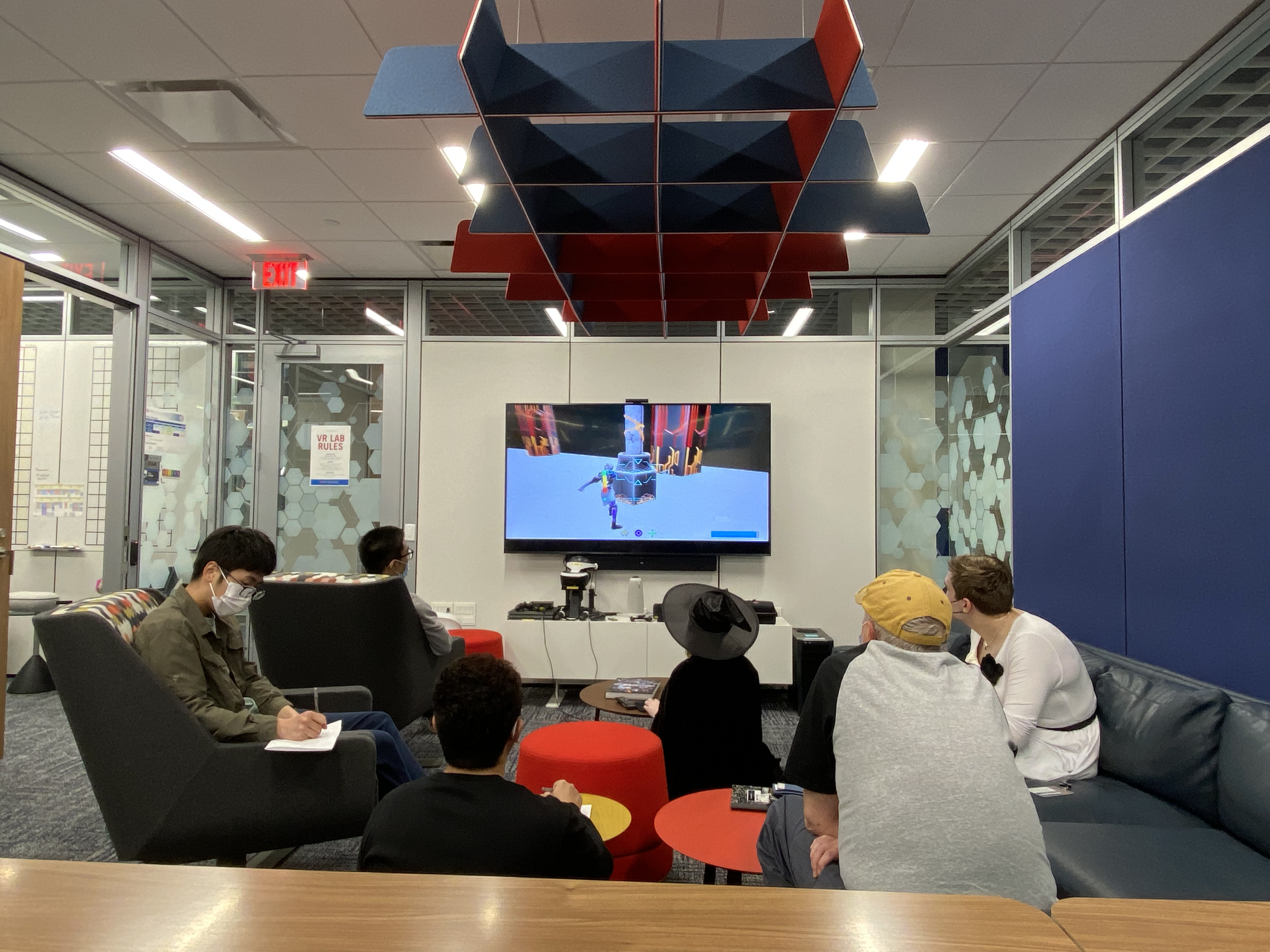 Photo of an art review with the art stakeholder. The art team is gathered around a TV with AGRYOS: Recovering Eden being streamed to it. The art team is taking notes.