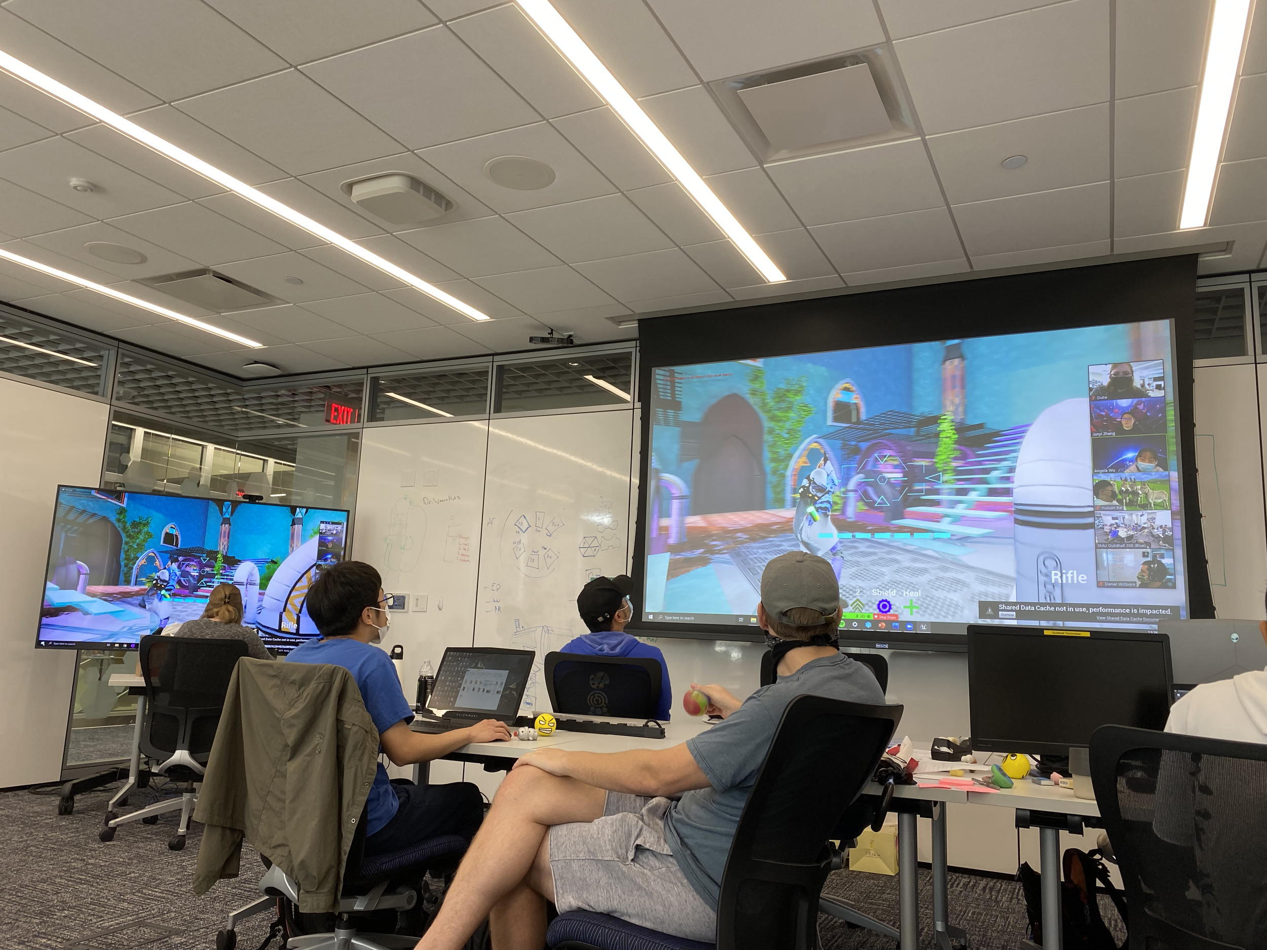 Photo of end-of-day presentations. Projected onto the wall is gameplay from AGRYOS: Recovering Eden.