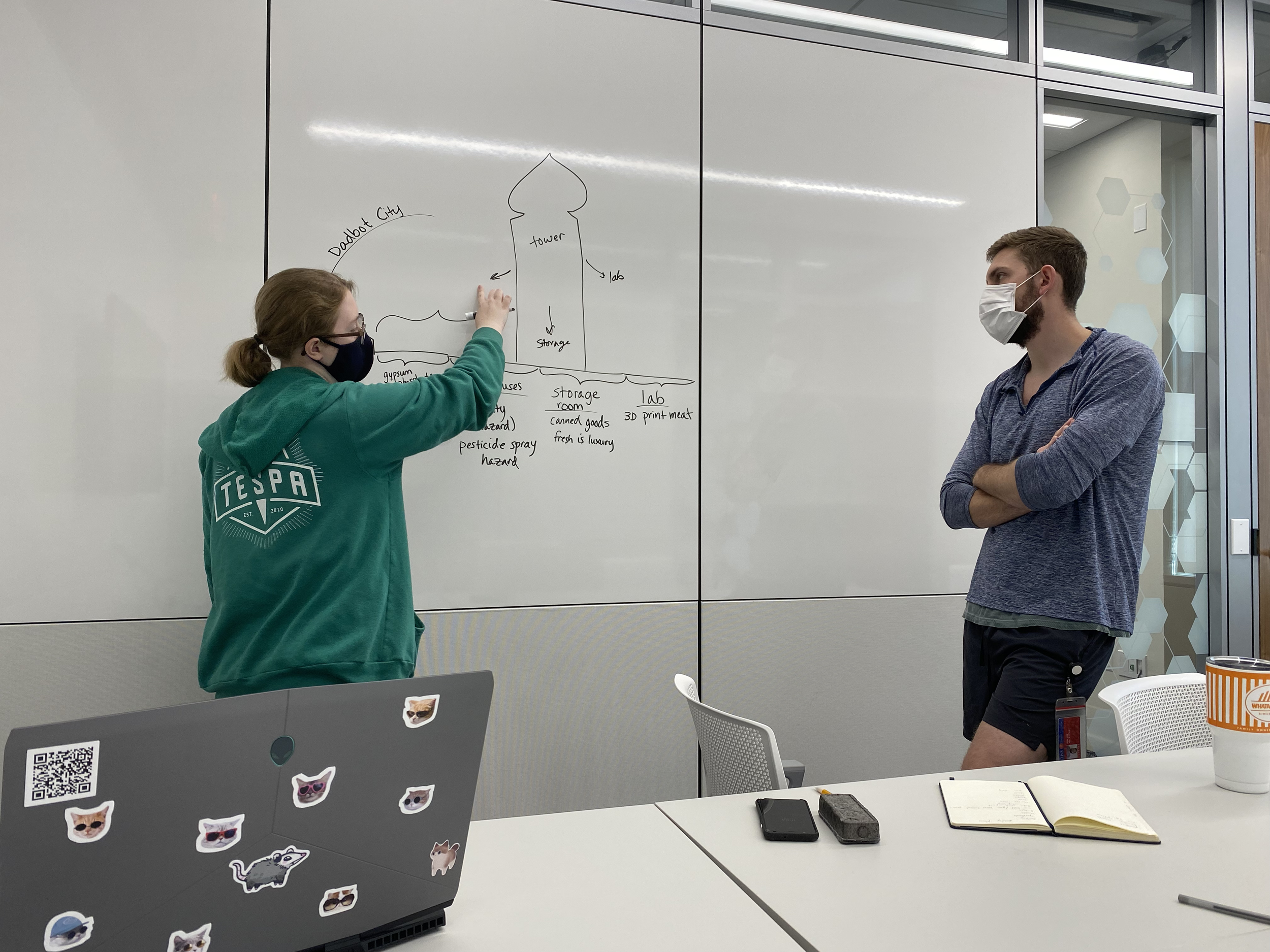 Photo of Dube and Dakota standing before a whiteboard, discussing the game's narrative and level design.
