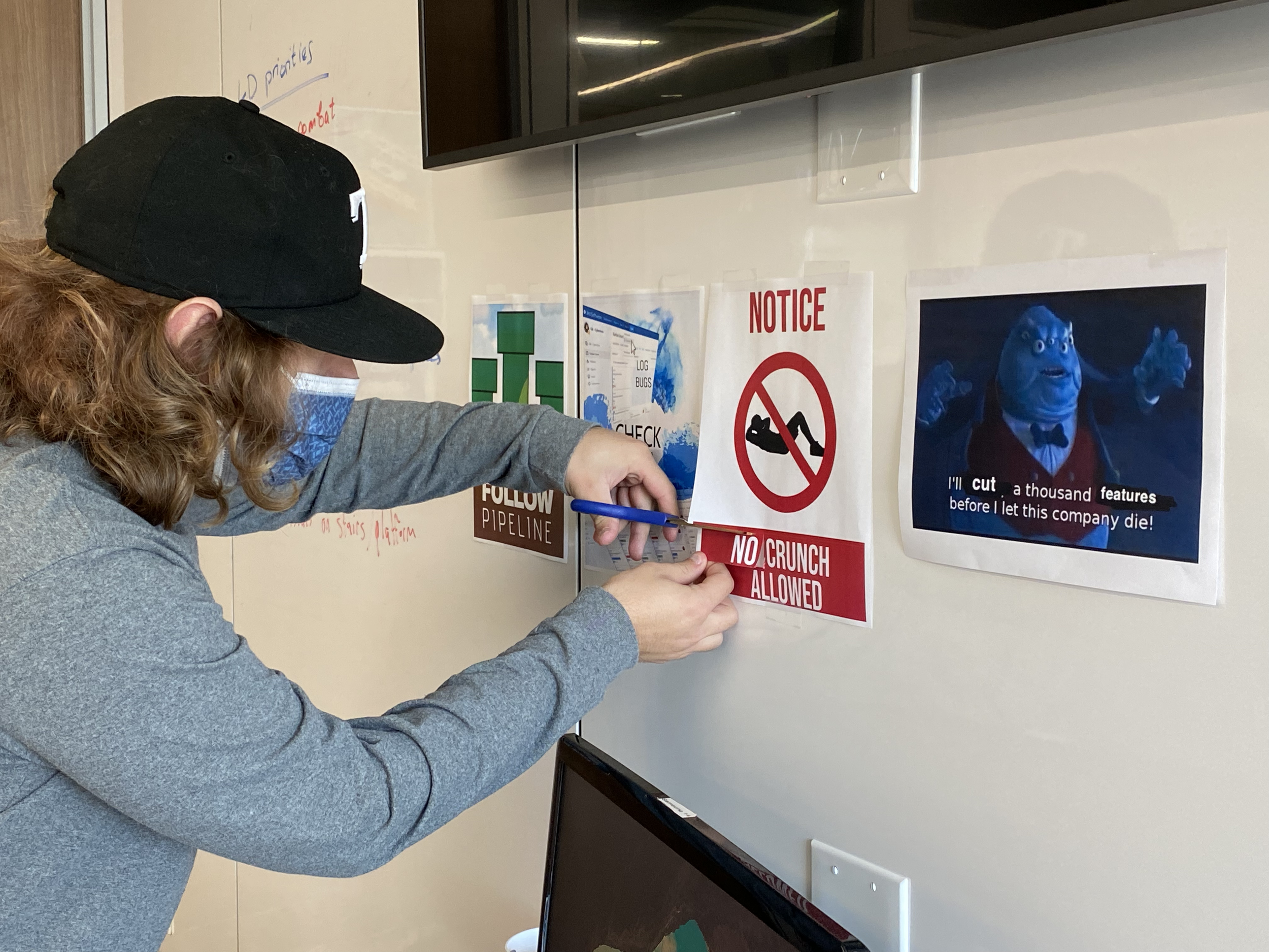 Photo of Cody cutting up a motivational poster. It originally said "No crunch allowed," but he's cutting out the word "no".